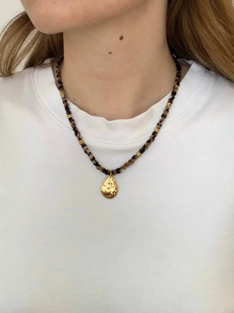 La femme porte le collier goutte dorée en acier inoxydable de chez Au Bonheur de Sophie